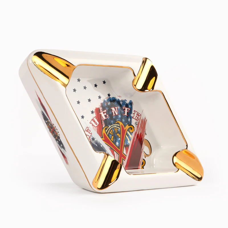 White ceramic square ashtray with shiny gold-tone corner accents and a patriotic blue-red inner design nearby the center marks the American flag motif.